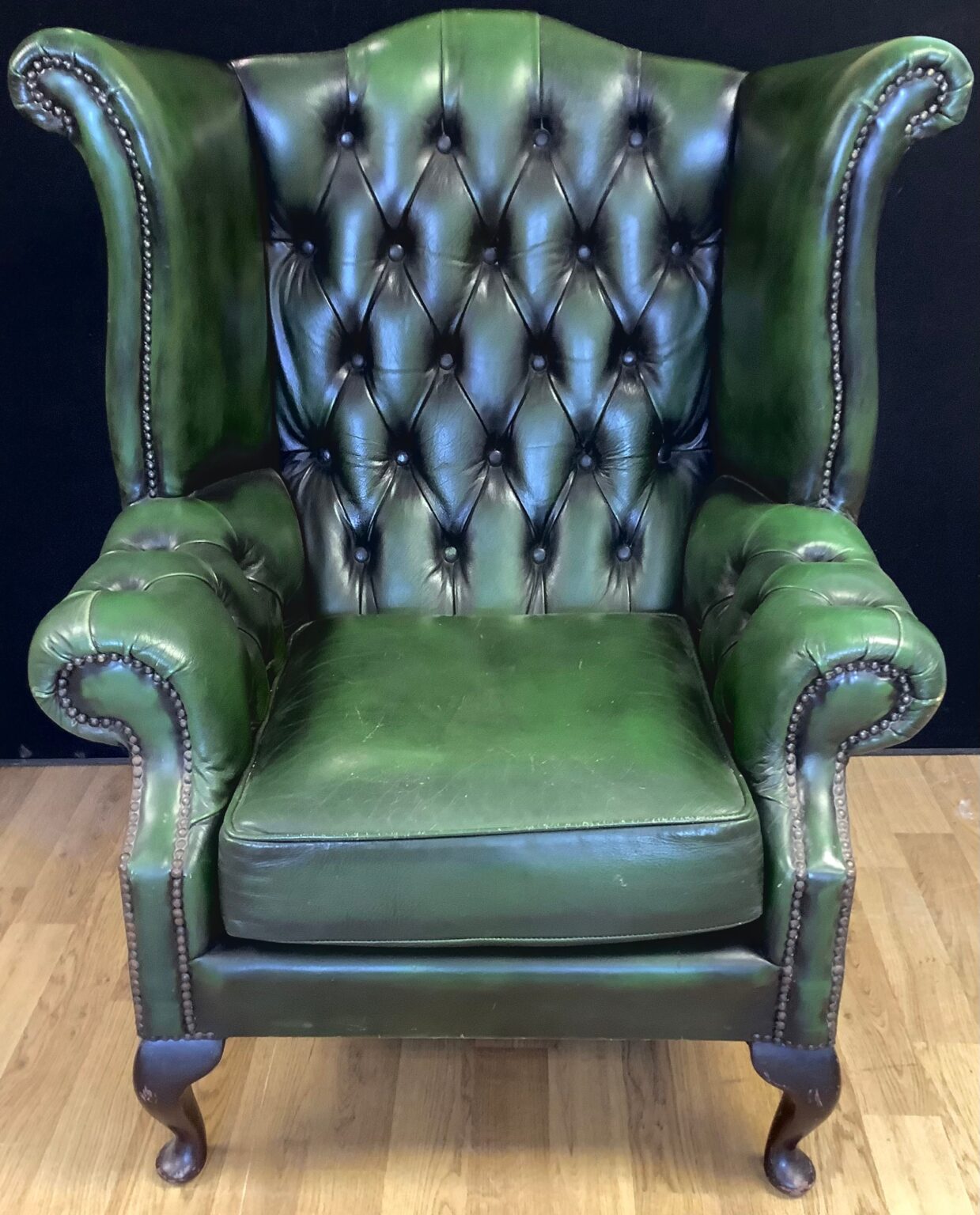 Green deep buttoned leather armchair with wings. Town and Country Antiques